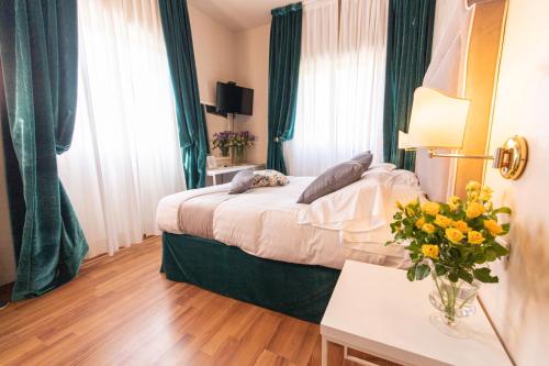 a hotel room with a bed and a vase of flowers at Hotel Viscardo in Forte dei Marmi