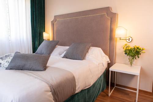 uma cama com duas almofadas e um vaso de flores em Hotel Viscardo em Forte dei Marmi