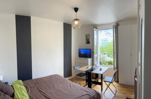 a bedroom with a bed and a desk and a window at Studio de charme in Pantin