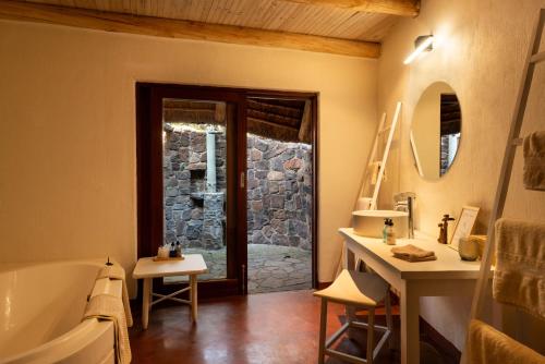 a bathroom with a tub and a sink and a mirror at Zebras Crossing in Modimolle