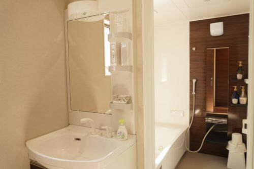 a white bathroom with a sink and a mirror at Muji House Osaka Sannan Hotel 大阪泉南酒店良築 in Tannowa