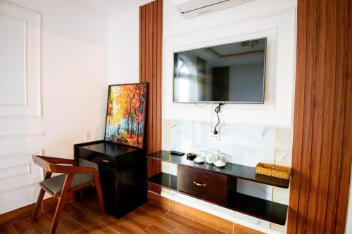 um quarto com uma secretária e uma televisão na parede em HÀ ANH hotel em Phường Sáu