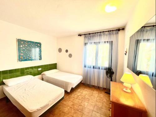 1 dormitorio con 2 camas, escritorio y ventana en Villa Menorquina en playa, en Cala Morell