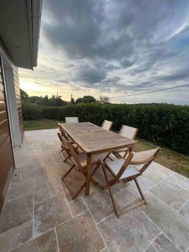 a wooden table and chairs on a patio at Magnifique maison piscine 15 min de Bordeaux et proche saint Emilion avec wifi in Sadirac
