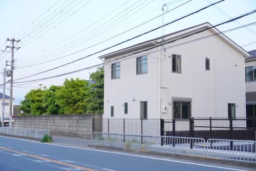 una casa blanca al lado de una calle en Muji House Osaka Sannan Hotel 大阪泉南酒店良築 en Tannowa