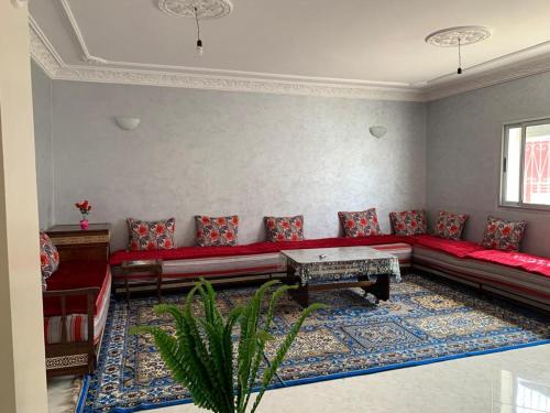 a living room with red couches and a table at Villa in Douar Ourlali
