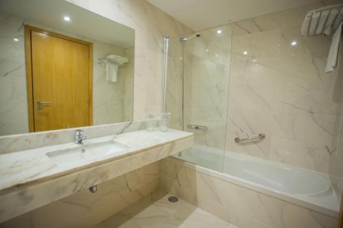 a bathroom with a sink and a tub and a shower at Hotel Brazão in Vila do Conde