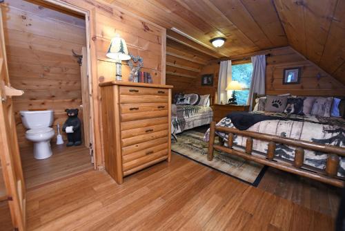 Dormitorio en cabaña de madera con cama y aseo en Big Pine - Long range mountain views, large decks, hot tub, fire pit and dog friendly!, en Blairsville