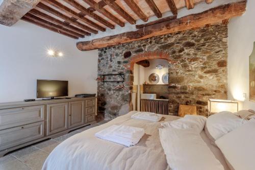 two beds in a bedroom with a stone wall at Palazzo Giusti, Understated Luxury with a Welcoming Ambience on the Hills of Lucca in Pescaglia