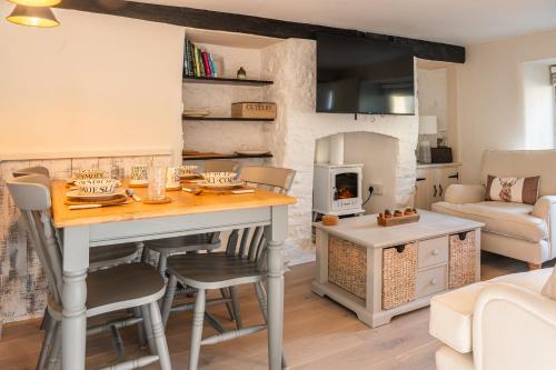 a kitchen and living room with a table and a fireplace at 2 Candlemas Cottage in Bourton on the Water