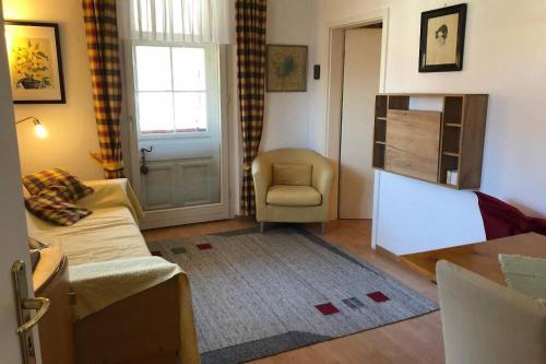 a living room with a couch and a chair and a door at Top-Appartement direkt an der Kampenwandbahn in Aschau im Chiemgau
