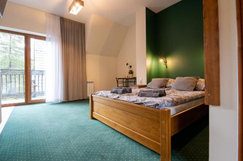 a bedroom with a large bed with a green wall at Apartamenty u Symuna in Zakopane