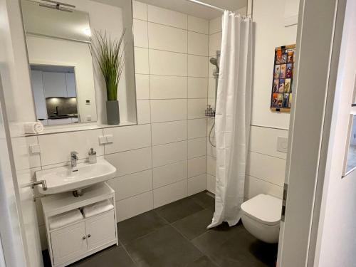 ein Badezimmer mit einem Waschbecken, einem WC und einem Spiegel in der Unterkunft Neubau – S-Bahn nah – Köln Messe/Hbf in Bergisch Gladbach