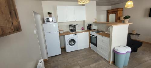 Il comprend une cuisine équipée d'un réfrigérateur blanc et d'un lave-linge. dans l'établissement La p'tite maison, à Londinières