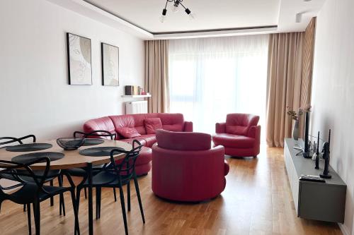 sala de estar con sofá rojo, mesa y sillas en Capital Towers - Apartament Red z widokiem na panoramę miasta i rzekę en Rzeszów