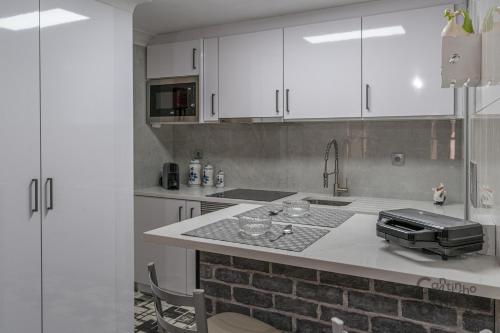 eine Küche mit weißen Schränken und einer Arbeitsplatte in der Unterkunft Cantinho dos Avós in Viana do Castelo