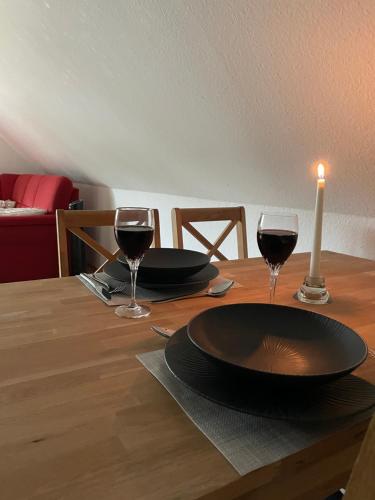 een tafel met twee glazen wijn en een kaars bij FeWo Im Loog in Großefehn 
