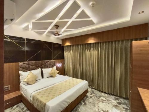 Hotel Prime Villa Gurukul في أحمد آباد: غرفة نوم بسرير كبير وسقف
