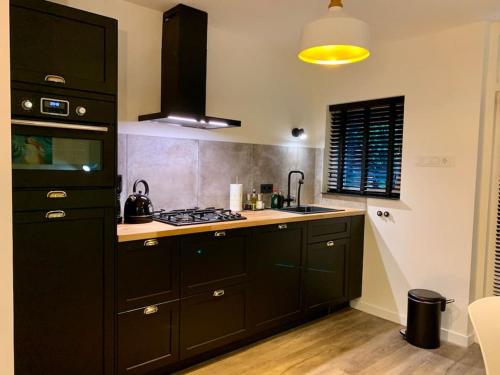 a kitchen with black cabinets and a stove at Veluwse Wolf: natuurlijk genieten! in Otterlo