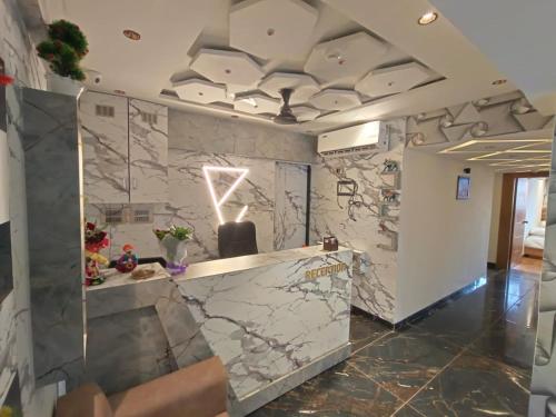 a lobby with a stone wall with a reception desk at Hotel Prime Villa Gurukul in Ahmedabad