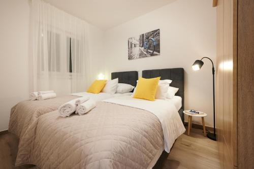 - une chambre avec un grand lit blanc et des oreillers jaunes dans l'établissement ZEN apartment, à Trogir