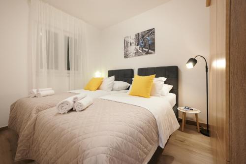 a bedroom with a large white bed with yellow pillows at ZEN apartment - private pool in Trogir