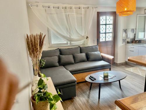 ein Wohnzimmer mit einem Sofa und einem Tisch in der Unterkunft le petit prince , jolie maisonnette terrasse Netflix parking privé jeux de société in Bourg-en-Bresse