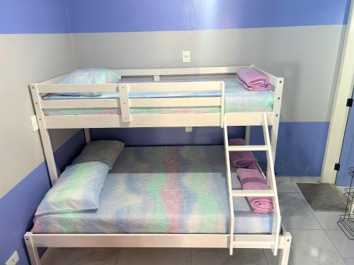 two bunk beds in a room with purple walls at Hostel Quintal de Casa in Foz do Iguaçu
