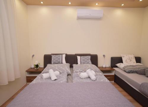 a bedroom with two beds with white pillows at Kinder Apartman in Makó