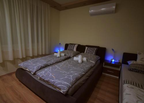 a large bed in a bedroom with blue lights at Kinder Apartman in Makó