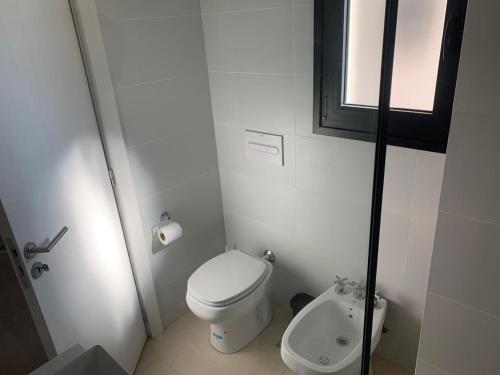 Un pequeño baño con inodoro y ventana. en Dpto Bastion del Este 103, en Tandil