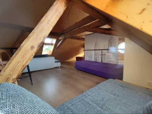 a attic room with a purple couch and a bed at Guesthouse ''Chatonnaye'' 