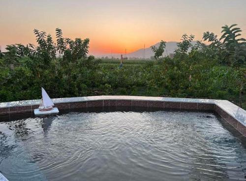 un pequeño velero en una piscina de agua con puesta de sol en Bedouin Lodge Luxor en Luxor