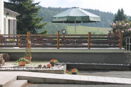 a patio with an umbrella and a table with flowers at Hotel Carolaruh in Bad Elster