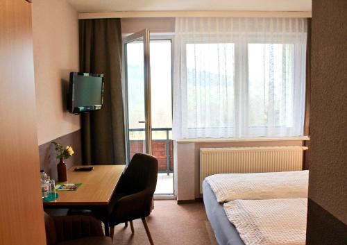 a hotel room with a desk and a bed and a window at Hotel Carolaruh in Bad Elster
