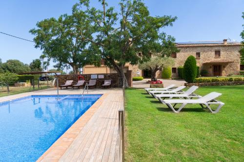 - une piscine avec des chaises longues à côté d'une maison dans l'établissement Masía Rural Can Poch, à Pals