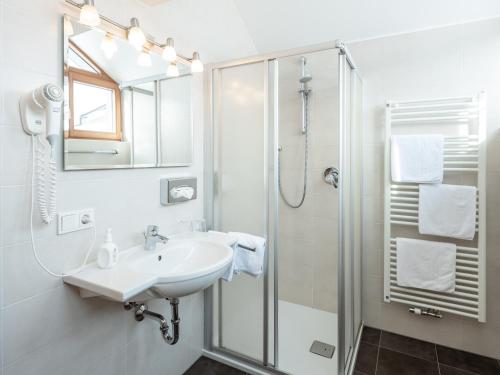 a white bathroom with a sink and a shower at Hotel Falken in Falzes