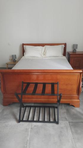 ein Bett mit einem Bettrahmen aus Holz und einer Bank in der Unterkunft Biganosconfort in Biganos