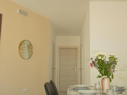 a dining room with a table with chairs and a vase of flowers at Side-seaview apartment near beach and close to St. Julians in Baħar iċ-Ċagħaq