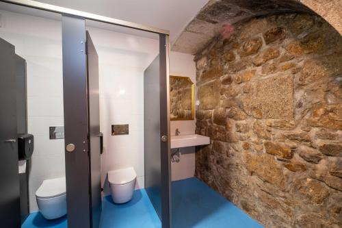 La salle de bains est pourvue de 2 toilettes et d'un mur en pierre. dans l'établissement Albergue Santiago de Caminha, à Caminha