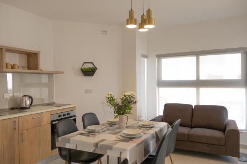 a kitchen and dining room with a table and a couch at Side-seaview apartment near beach and close to St. Julians in Baħar iċ-Ċagħaq