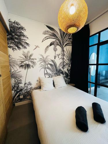 - une chambre avec un grand lit blanc et du papier peint en palmier dans l'établissement Joli T2 Moderne au Coeur de Marseille - Place Castellane, à Marseille