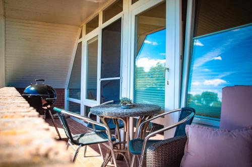 una mesa y sillas en un porche con ventana en Staberhuk Baben - großer sonniger Balkon - XL Wohnung en Staberdorf