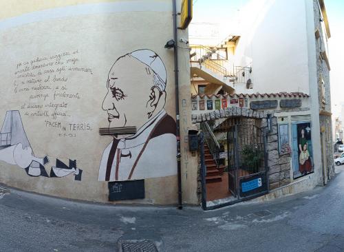 una pintura de un hombre al lado de un edificio en b&b il Portico Orgosolo en Orgosolo