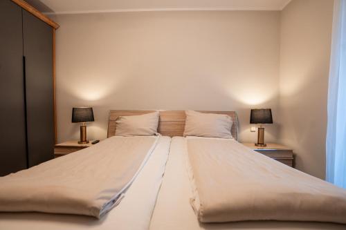 a large bed in a bedroom with two lamps on tables at Hotel CityHome am Kurpark in Bad Salzuflen