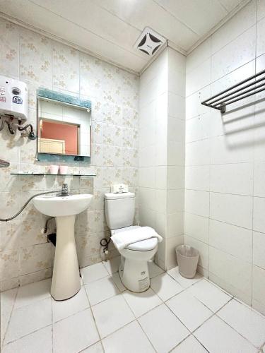 a white bathroom with a toilet and a sink at Rowan House in Taichung