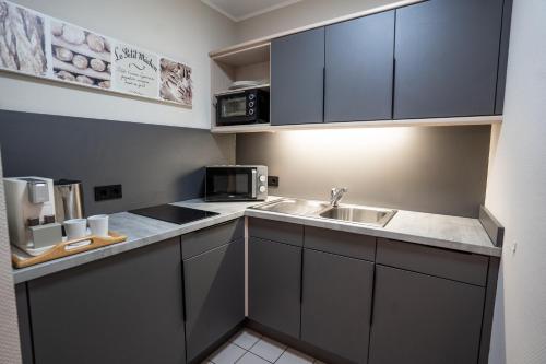 a small kitchen with a sink and a microwave at Hotel CityHome am Kurpark in Bad Salzuflen