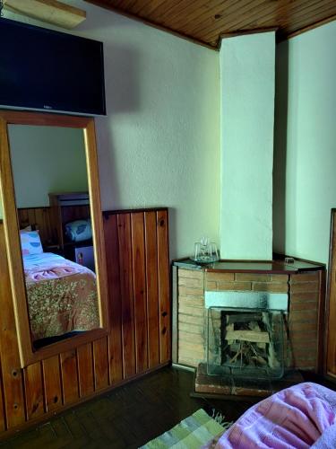 a room with a fireplace and a mirror and a bed at Pousada Solar das Flores Maringá RJ Visconde de Mauá in Visconde De Maua