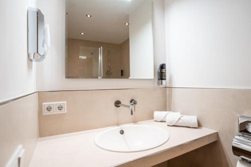 a bathroom with a sink and a mirror at Hotel CityHome am Kurpark in Bad Salzuflen