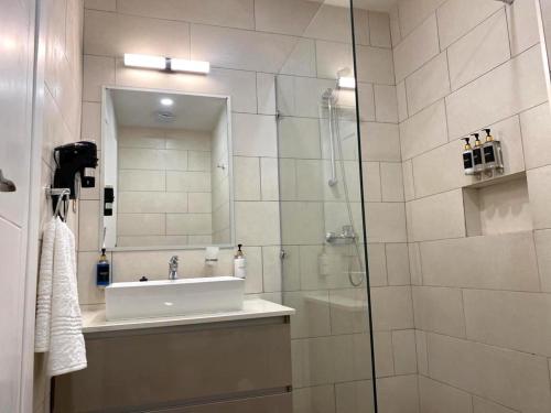 a bathroom with a sink and a shower with a mirror at 24 Roma in Lusaka